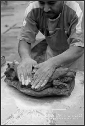 And an artisan spreads the Tierra clay with his hands.